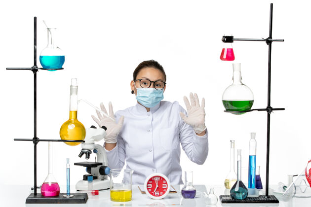 病毒前视图穿着医疗服的女化学家带着面罩坐在白色背景上 溅起了病毒化学冠状病毒-实验室化学医生面罩