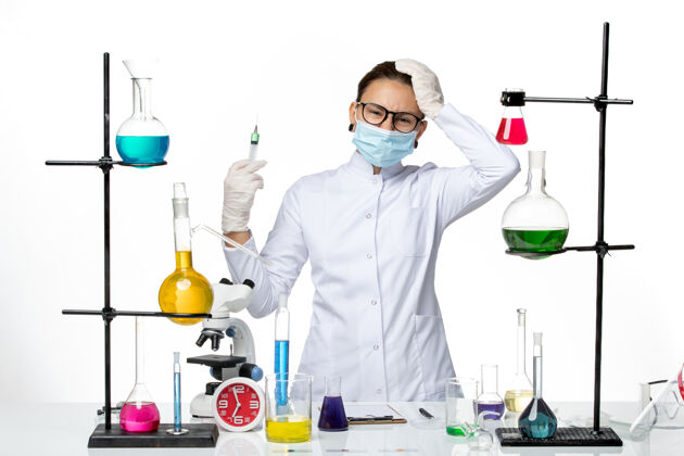 注射前视图：身穿医疗服的女化学家 戴着面罩 在白色背景上拿着注射液病毒化学实验室covid-splash前面科学西装