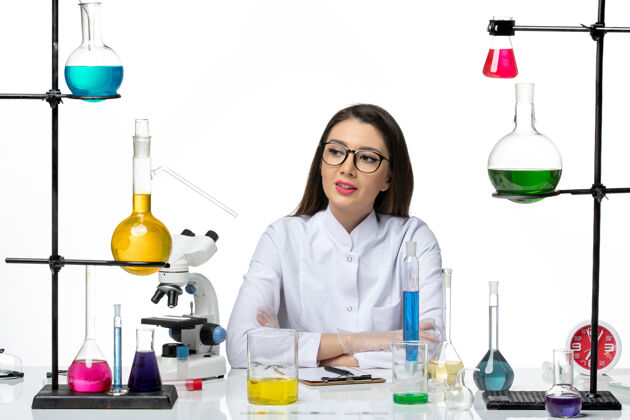 计算机前视图穿着白色医疗服的女化学家在浅白色背景上工作和写笔记科学病毒covid-大流行实验室微笑视图病毒