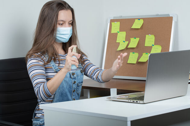 面具女员工使用基本的消毒工具保持办公室无菌喷雾外科姿势