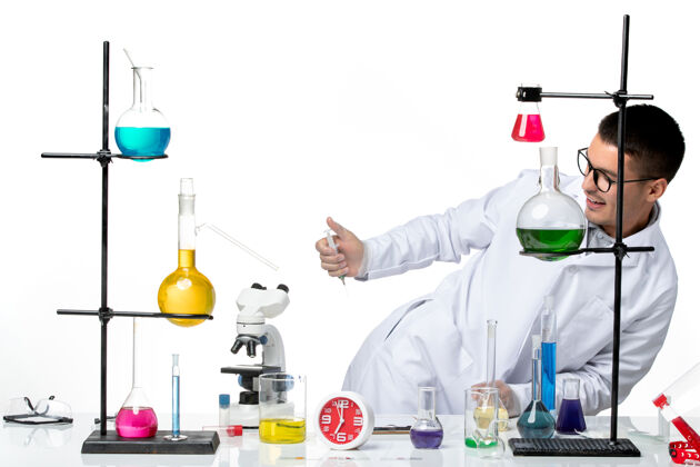 实验室前视图男性化学家穿着白色的医疗服 在桌子前拿着白色背景的解决方案实验室病毒科学冠状病毒大流行烧杯医疗视图