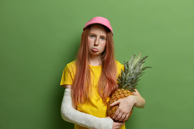磨损伤心得罪了满脸雀斑的红发女孩 被父母惩罚 抱着多汁的菠萝 撅着嘴 神情阴郁 在做冒险运动时受伤 对着绿墙摆姿势忧郁破碎悲伤