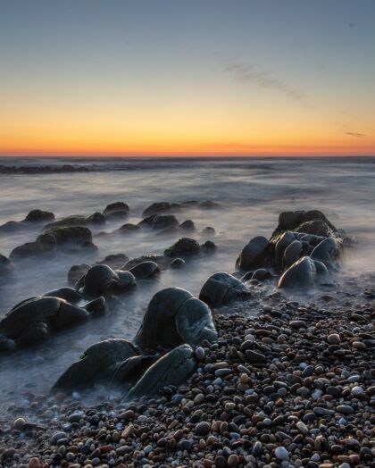 日落一个美丽的落日在岩石海滩垂直拍摄颜色风景海岸线