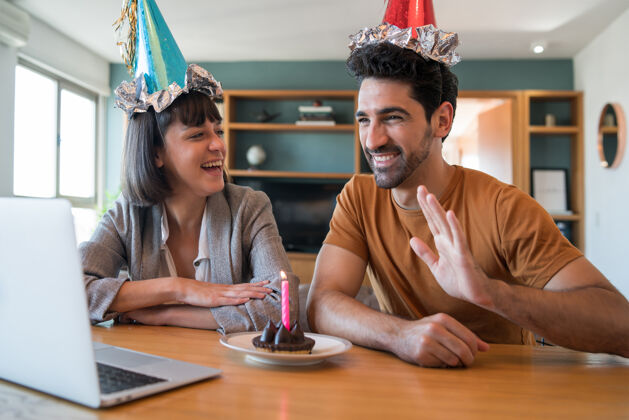 享受一对夫妇在家里用笔记本电脑通过视频通话庆祝生日的照片夫妇在隔离时间在线庆祝生日新的正常生活方式概念生日室内聊天