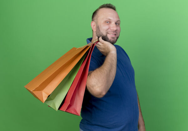 成人面带微笑的成年斯拉夫男子肩上扛着购物袋 看上去很孤独人抱包