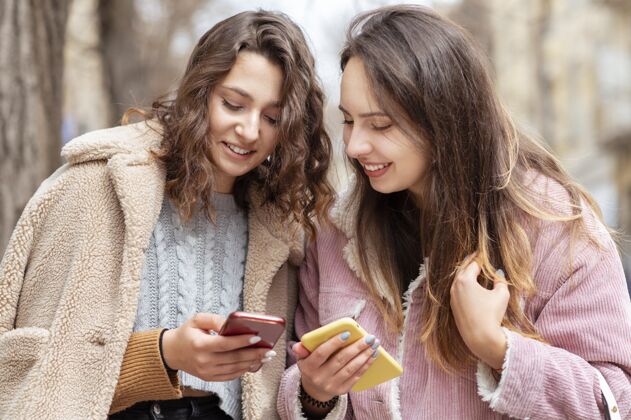 年轻拿着智能手机的中枪女人水平友谊女人