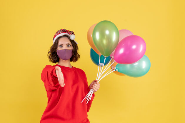颜色正面图年轻女性拿着气球 戴着黄色的无菌面具聚会消毒气球
