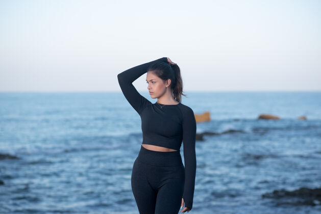 女性年轻的拉丁女性穿着黑色运动服 站在沙滩上摆姿势女士运动运动服