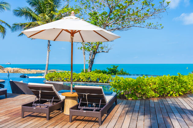 海岸酒店度假区室外游泳池周围的雨伞和椅子 可欣赏海景 适合旅游度假享受椰子树家具