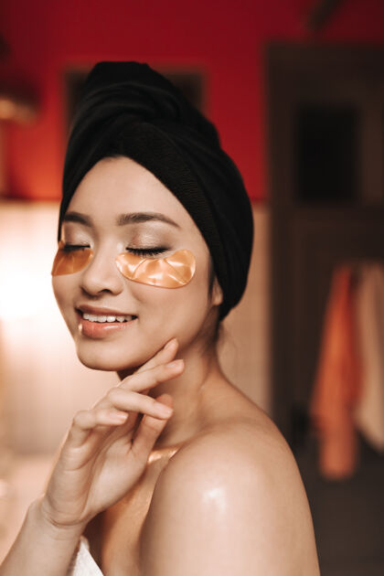 脸没有化妆的亚洲女人用毛巾和金色眼罩摆姿势皮肤护理美丽常规