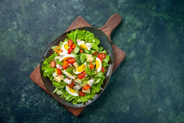 许多俯瞰美味的沙拉与许多新鲜的原料在木制砧板上黑绿色混合色的背景沙拉平底锅炊具