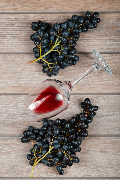 顶视图一堆黑葡萄和一杯葡萄酒放在木桌上高质量的照片酒杯桌子自然