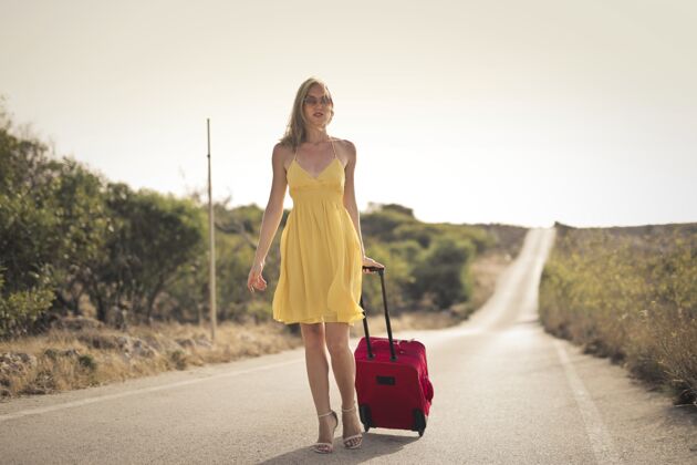 女人街上穿着黄色连衣裙和红色手提箱的女人孤独漂亮连衣裙