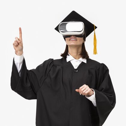 虚拟现实穿着毕业礼服戴毕业帽戴着虚拟现实耳机的女人设备毕业帽女性