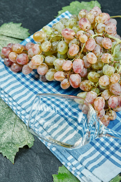有机一束红葡萄和一个蓝色桌布上的酒杯高品质的照片季节食物多汁
