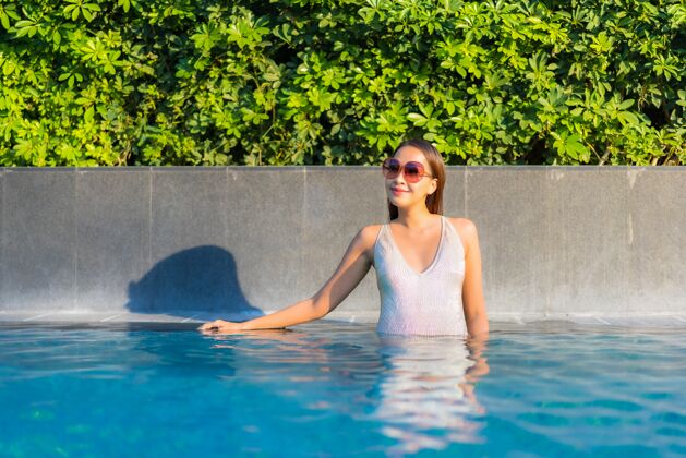人美丽的年轻女子在游泳池放松的画像度假村年轻女性