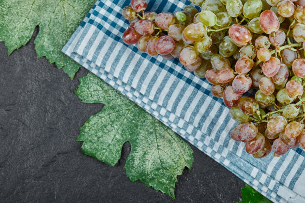 新鲜一束深色背景上有叶子的红葡萄高质量的照片桌布自然膳食