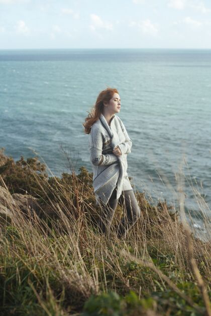自然一个女人站在岸边的垂直镜头 背景是大海景观草成人