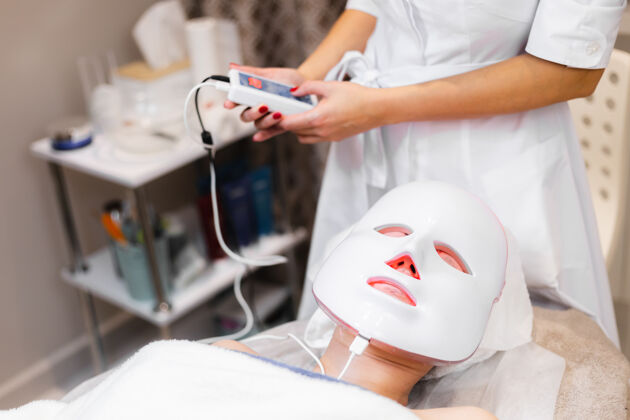 诊所客户躺在美容桌上的沙龙里 脸上戴着白色的面具面部成人女性