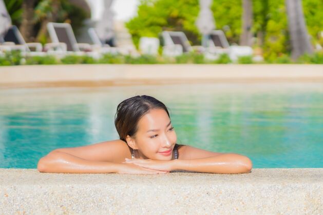 周末肖像美丽的亚洲年轻女子放松微笑休闲在户外游泳池周围与大海在旅游度假阳光海滩水疗