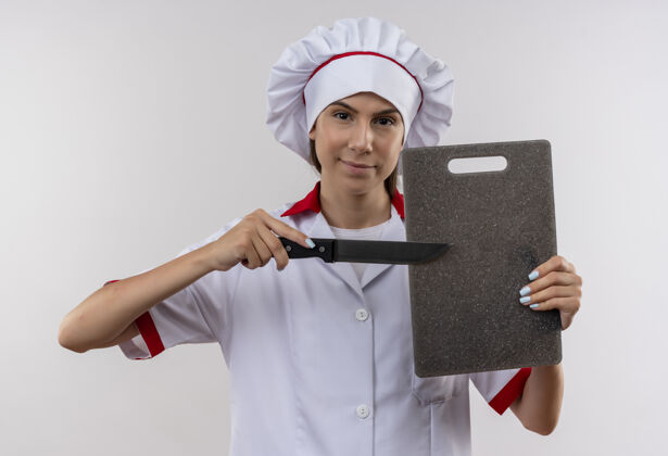 厨师年轻自信的白人厨师女孩穿着厨师制服 拿着剪纸和刀 在白色背景上与复印空间隔离开来董事会年轻信心