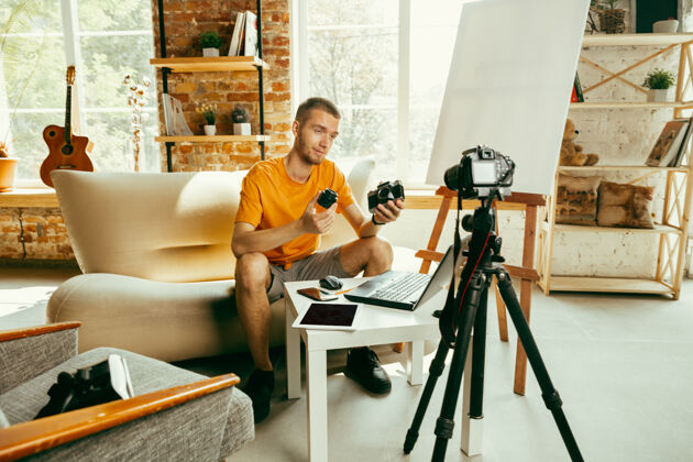 评论年轻的白人男性博主 带着专业设备 在家里录制摄像机的视频评论博客 视频博客 视频博客关于照片或技术新颖性的男人制作视频博客或直播流现场技术男性