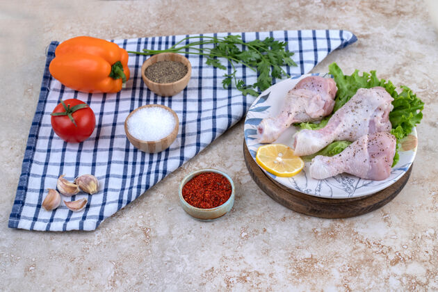胡椒粉生鸡腿肉和蔬菜放在木板上食物肉生的