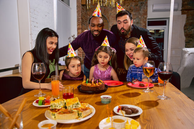 脸快乐的多民族家庭在家里庆祝生日的画像大家庭一边吃零食一边喝葡萄酒 一边问候和款待孩子庆祝 家庭 聚会 家的概念蛋糕爸爸微笑