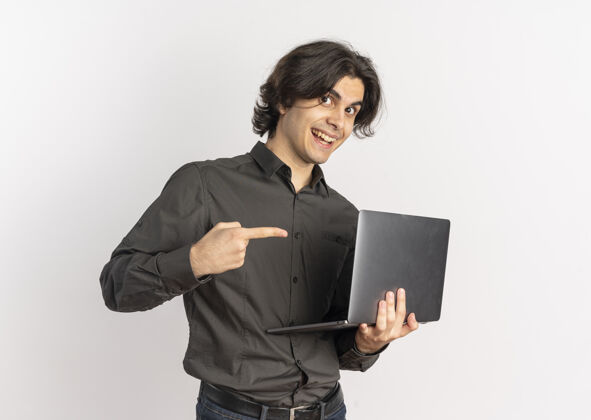 拿着年轻帅气的白人男子拿着笔记本电脑 指着它 笔记本电脑的背景是白色的 还有复印空间惊喜帅气笔记本电脑