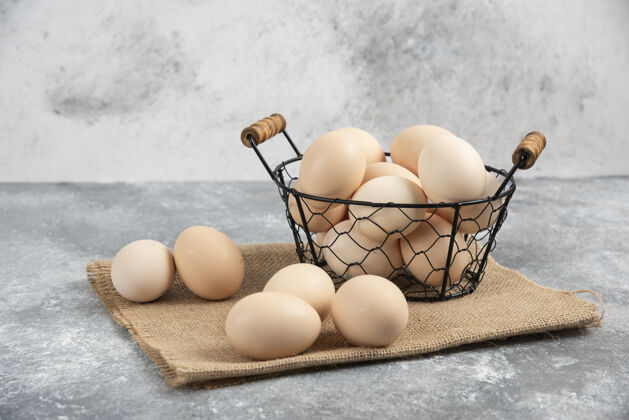 生的柳条篮子的生有机鸡蛋放在大理石上烹饪烹饪粗麻布