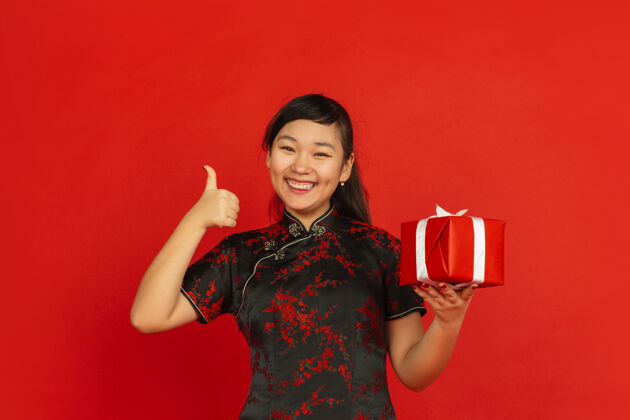 普通话2020年中国新年红色背景上的亚洲少女肖像穿着传统服装的女模特带着礼品盒看起来很开心庆祝 节日 情绪表现得很好 微笑着亚洲庆祝愿望