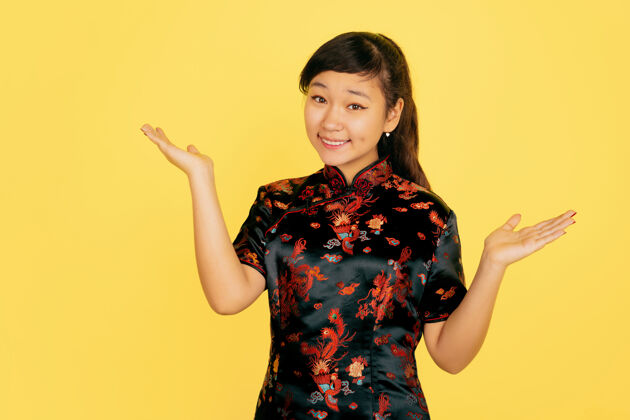 中国可爱的微笑 诱人的2020年中国新年快乐黄色背景上的亚洲少女肖像穿着传统服装的女模特看起来很快乐庆祝 人类情感复制空间旗袍季节女性
