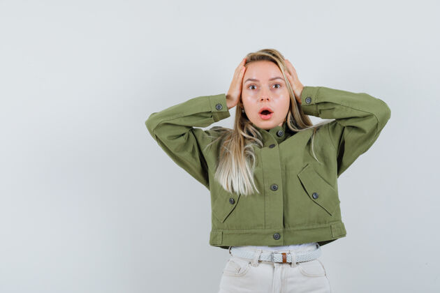 压力年轻女性双手抱着头 穿着绿色夹克 牛仔裤 看上去很有压力 前视图完美年轻夹克