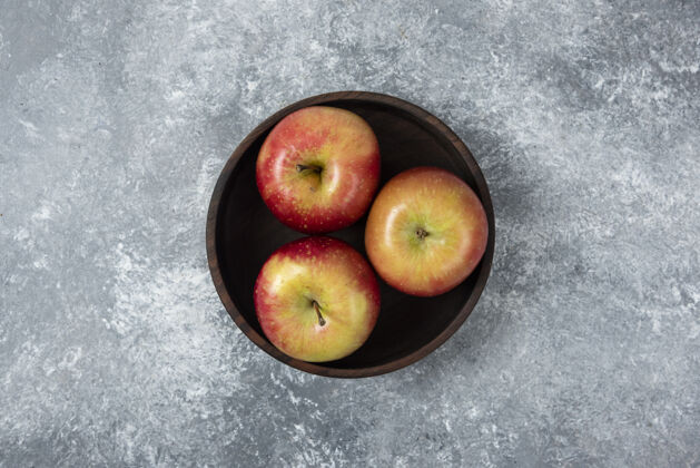 木板在大理石表面放上一碗鲜亮的苹果成熟木材自然