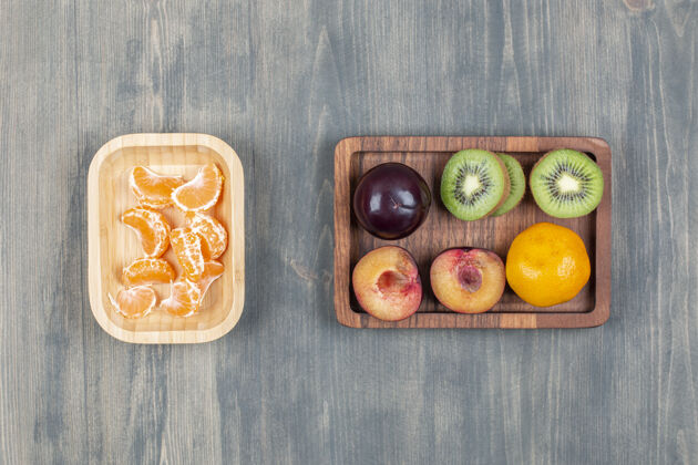 食物把新鲜的猕猴桃切成片 放在木板上 配上橘子和李子美味李子美味