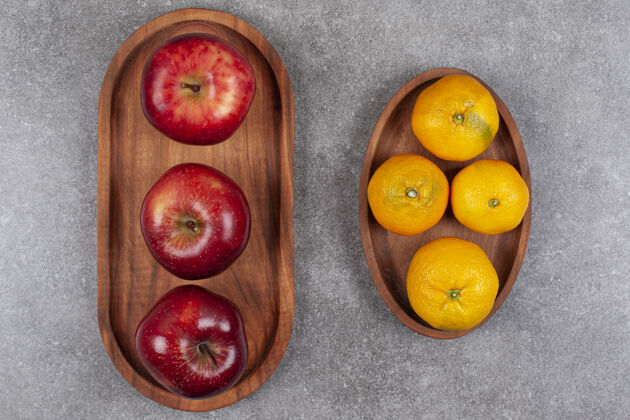 苹果木板上有红苹果和甜橘子橘子有机多汁