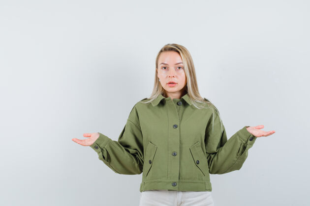 皮肤穿着绿色夹克的年轻女性表现出无助的姿态 看起来很不高兴前视图夹克无助女孩