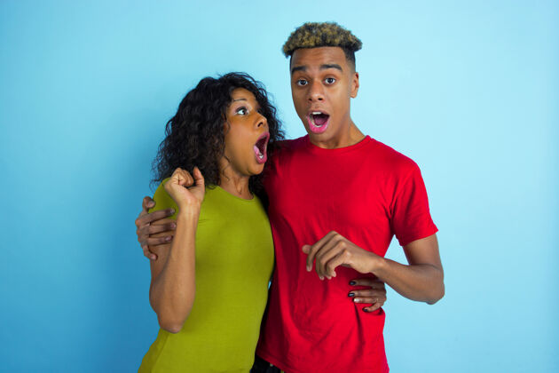 笑害怕 好奇 震惊年轻情绪化的非洲裔男女 穿着蓝色背景的彩色衣服美丽的情侣人类情感的概念 面部表情 关系 广告化妆品广告男性