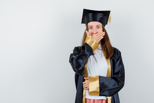 证书女毕业生的肖像 手放在嘴上 穿着学院服 看着震惊的前景色保持学术人