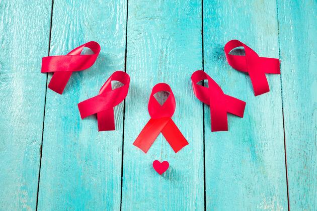 十二月艾滋病宣传标志蓝色木质背景上的红丝带世界艾滋病日概念健康 帮助 关怀 支持 希望 疾病 保健概念希望国际慈善