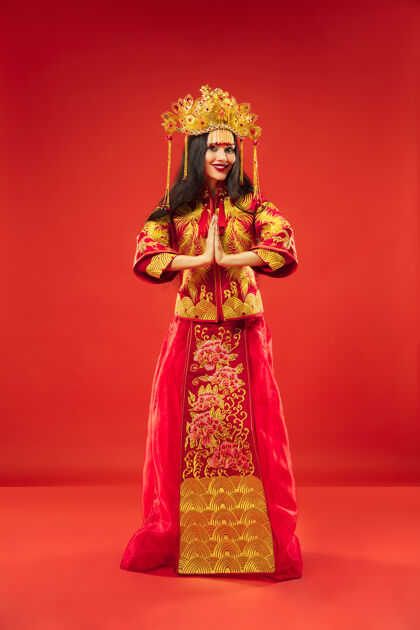 女性中国传统的优雅女子在摄影棚的红色背景美丽的女孩穿着民族服装中国新年 优雅 优雅 表演者 表演 舞蹈 女演员 服装的概念肖像文化情感