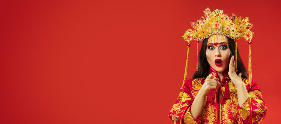 服饰中国传统的优雅女子在摄影棚的红色背景美丽的女孩穿着民族服装中国新年 优雅 优雅 表演者 表演 舞蹈 女演员 服装的概念民俗女性指向