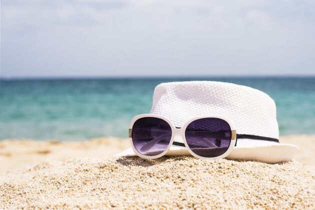 自然在沙滩上选择聚焦拍摄太阳镜和白帽子放松眼镜帽子