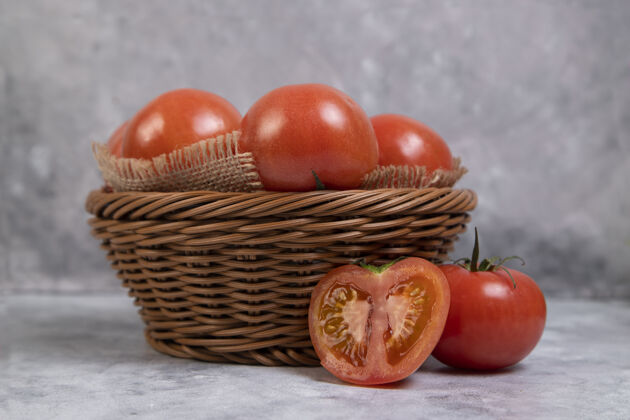 成熟整个多汁的红色西红柿放在柳条篮子里放在大理石上自然烹饪西红柿