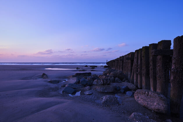 海岸美丽的日落景色 紫色的云彩覆盖着海滩上的栅栏海景观日落