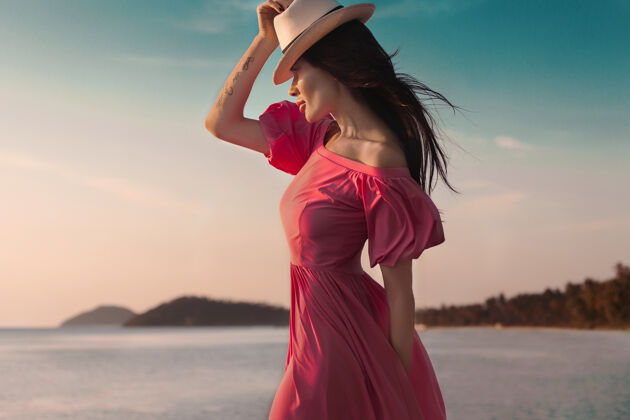 裙子户外夏日风情女人 阳光时尚写真性感女人穿粉色洋装在沙滩上日落在海边完美时尚风格