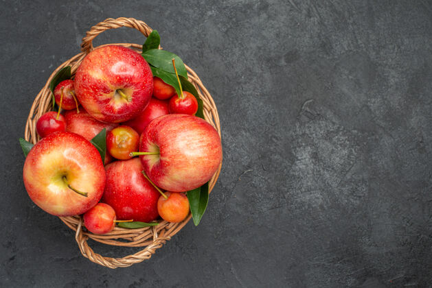 苹果顶部特写镜头：深色桌子上篮子里的水果 樱桃和苹果健康餐桌多汁