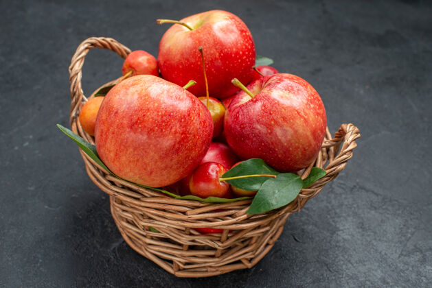 多汁侧边特写查看水果苹果和樱桃与树叶篮子在黑暗的桌子上石榴食物美味