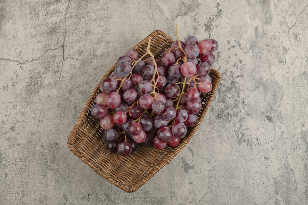 健康柳条篮美味的红葡萄放在大理石桌上自然食物顶视图