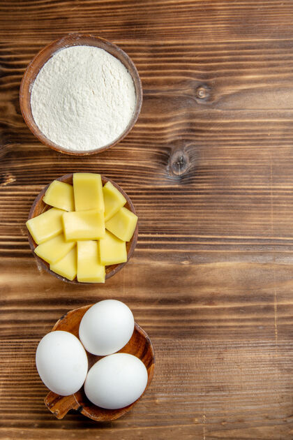 灰尘俯视整个生鸡蛋 用面粉和奶酪放在棕色的桌子上 鸡蛋面团 面粉 灰尘制品风景生的香薰